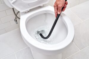 Plumber unclogging toilet choke using professional equipment in Singapore HDB